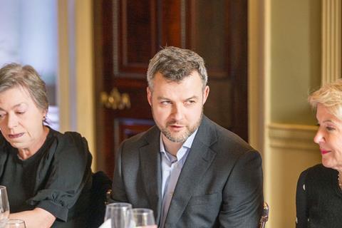 Three delegates engage in a discussion about insurance fraud at a roundtable.